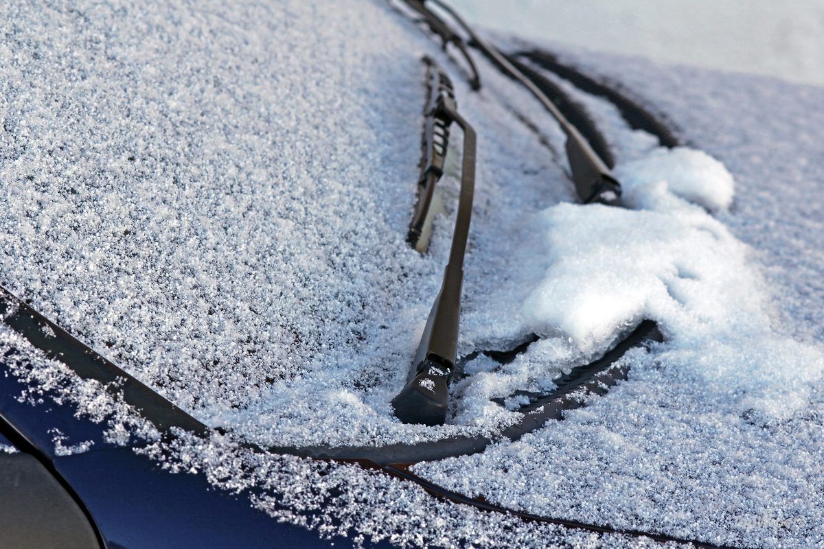 Wiper blade clearing a snow-covered windscreen on a frosty morning in Europe