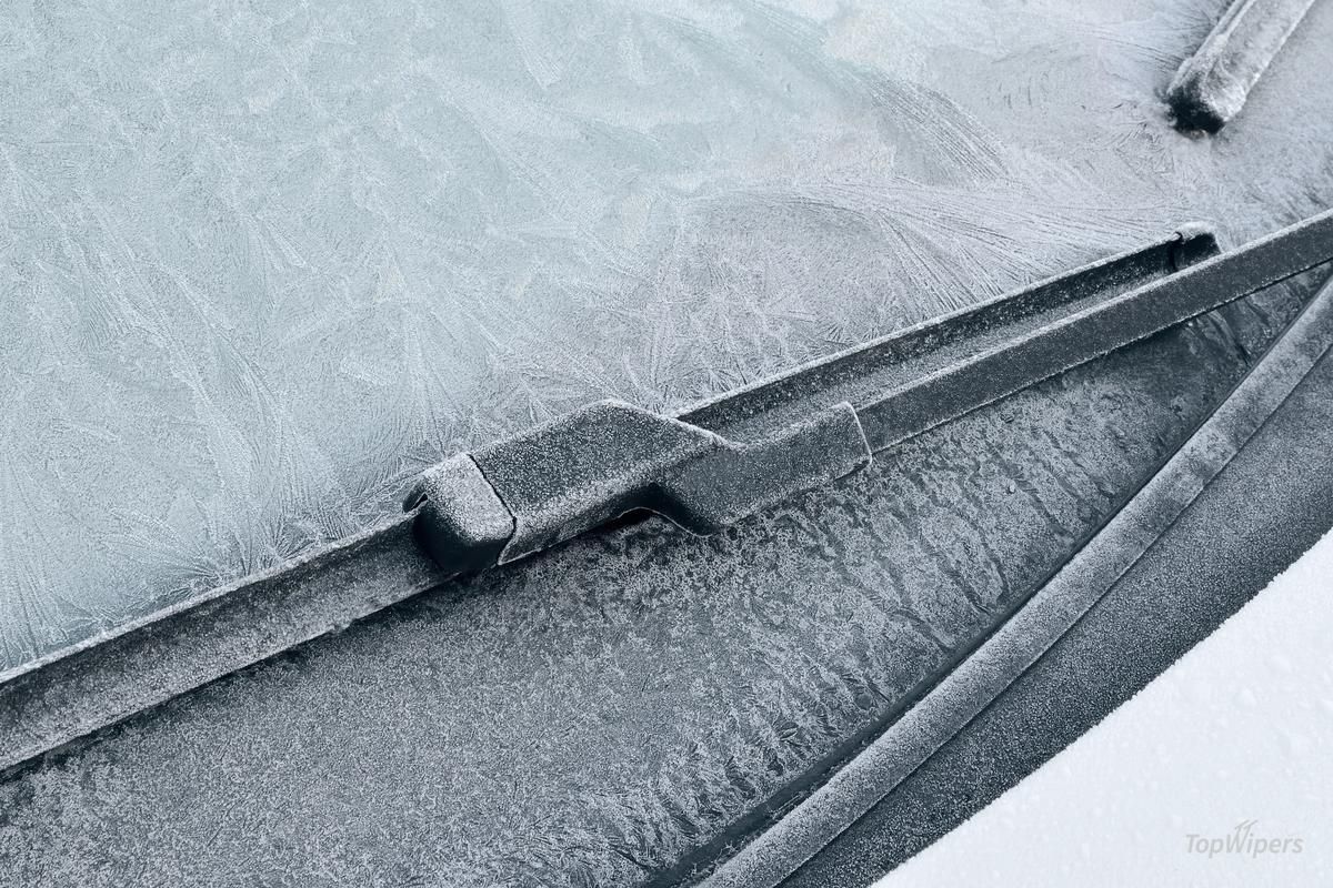 Nahaufnahme eines Wischergummis mit Eiskristallen auf vereister Frontscheibe